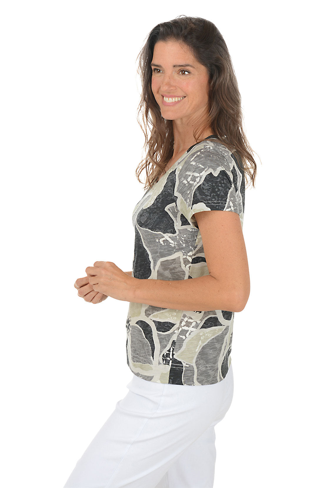 Woman wearing a floral patterned shirt on a white background. Side shot.