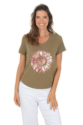 Woman wearing a green t-shirt with a pink floral design on a white background.