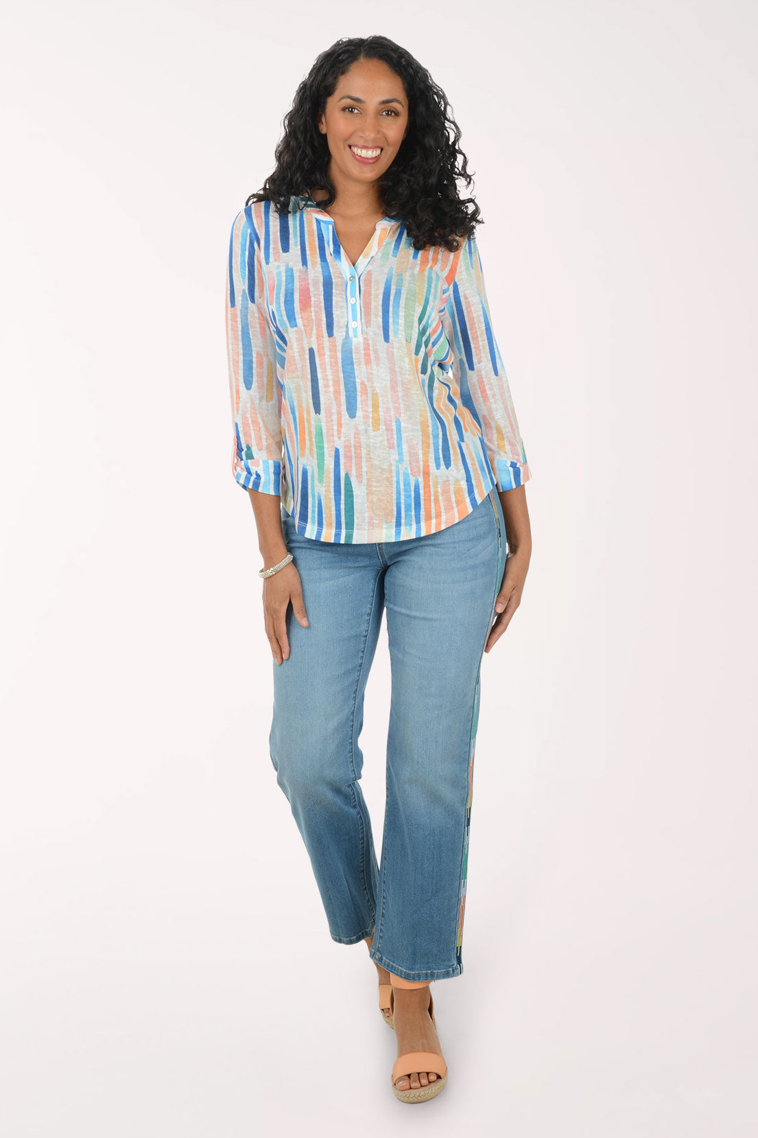 Woman wearing a colorful striped shirt and blue jeans on a white background