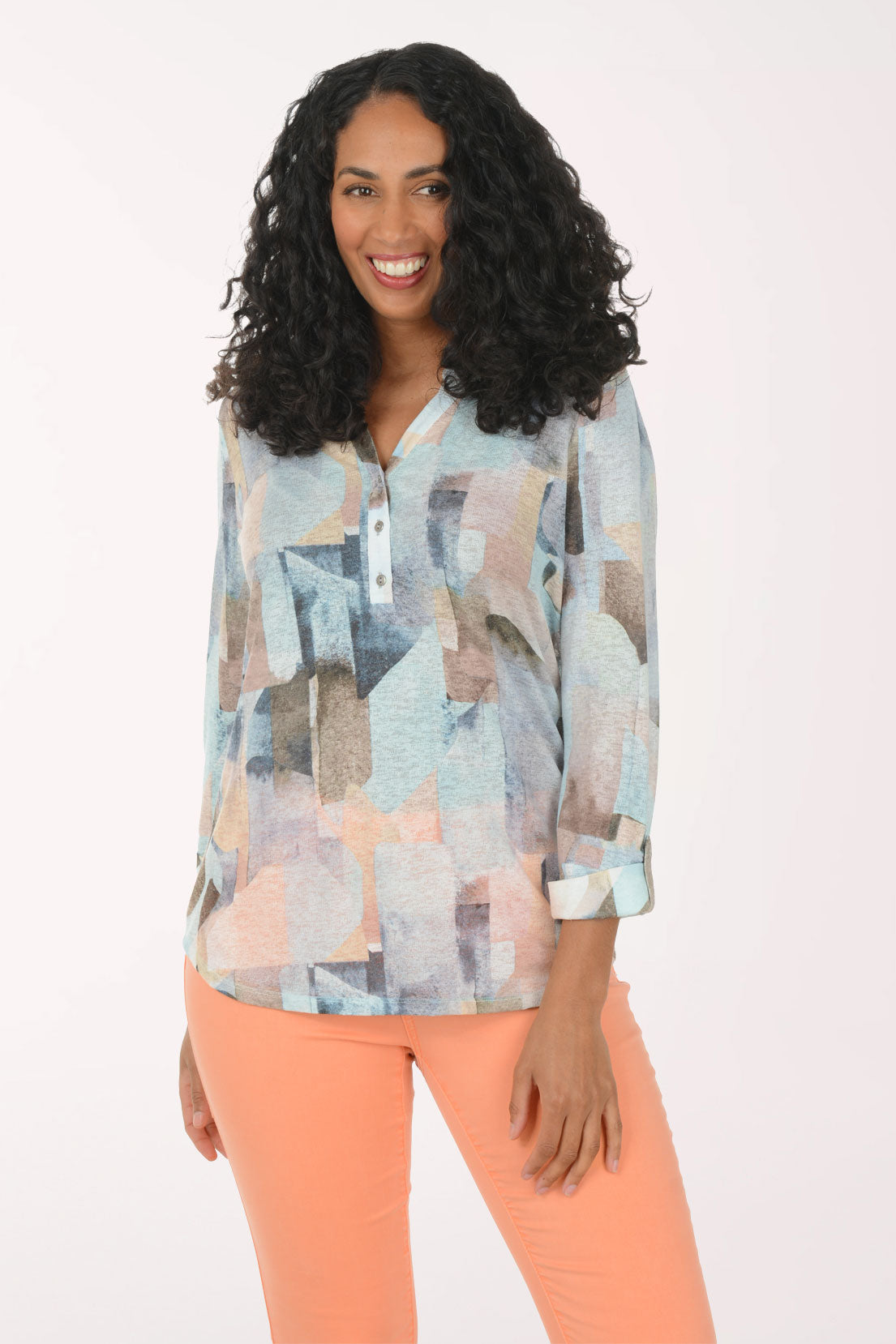 Woman wearing a patterned blouse and orange pants on a white background