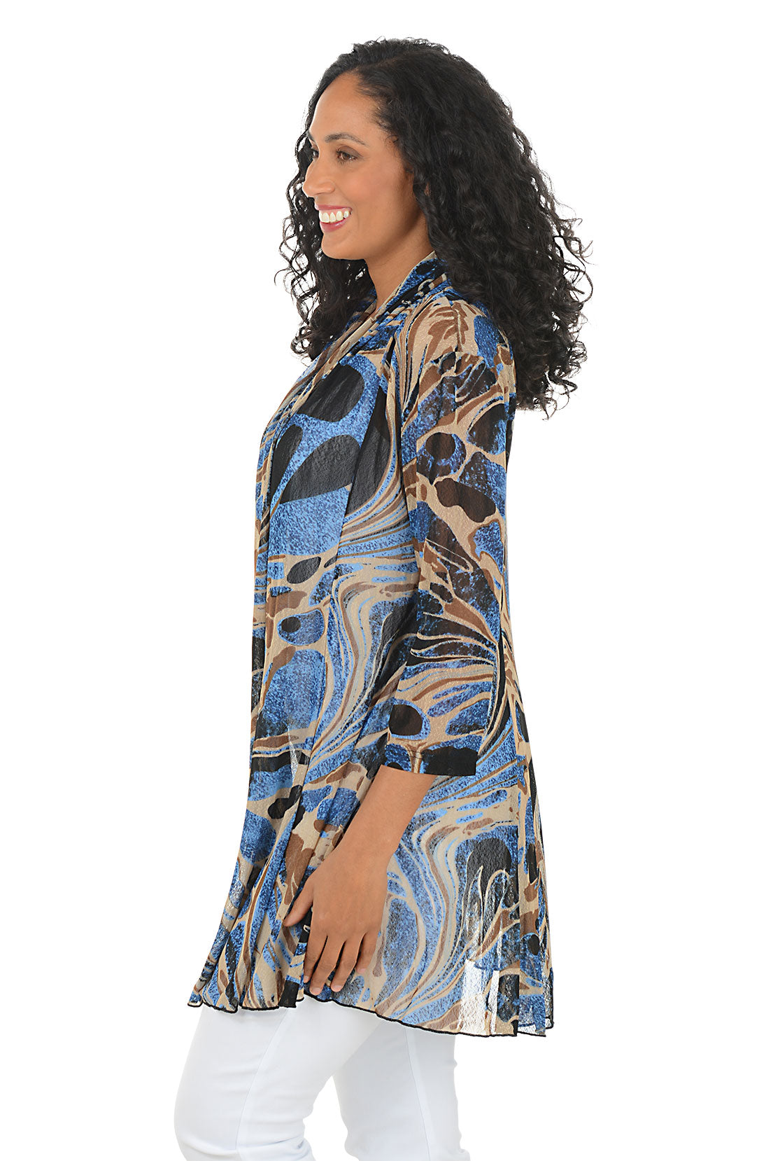 Woman wearing a patterned cardigan over a white top and pants on a white background. Side shot.