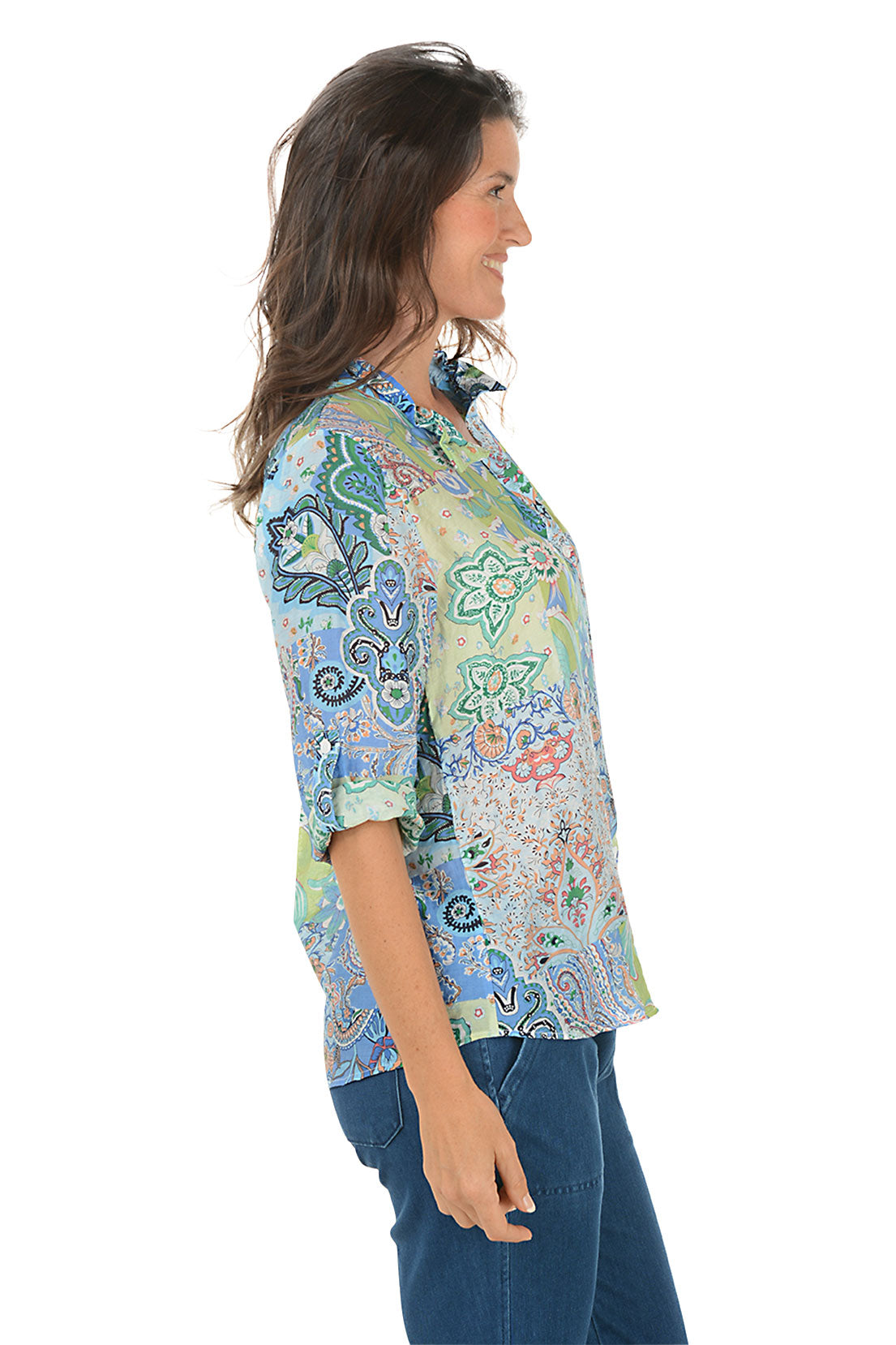 Woman wearing a colorful patterned shirt on a white background. Side shot.