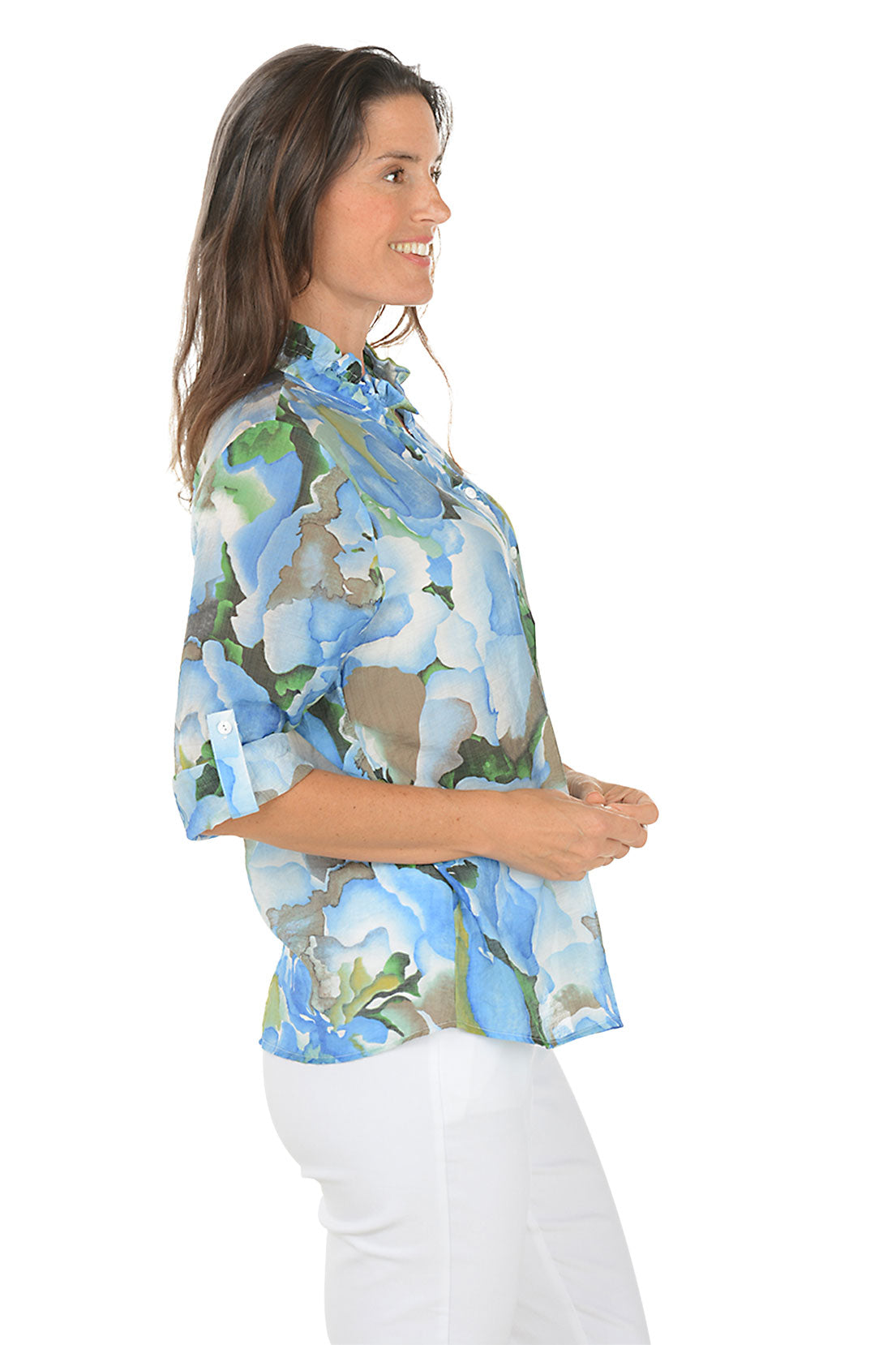 Woman wearing a floral blouse with a white background. Side shot.