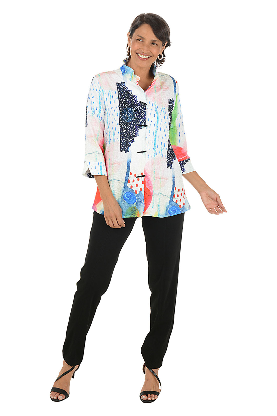 Woman wearing a colorful patterned blouse and black pants on a white background