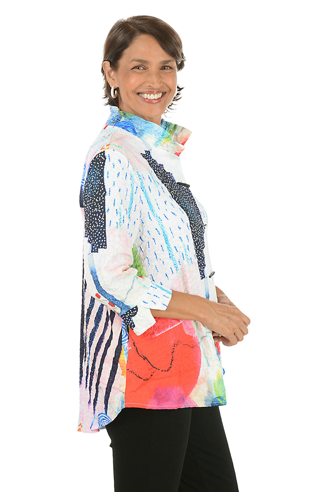 Woman wearing a colorful patterned blouse on a white background. Side shot.