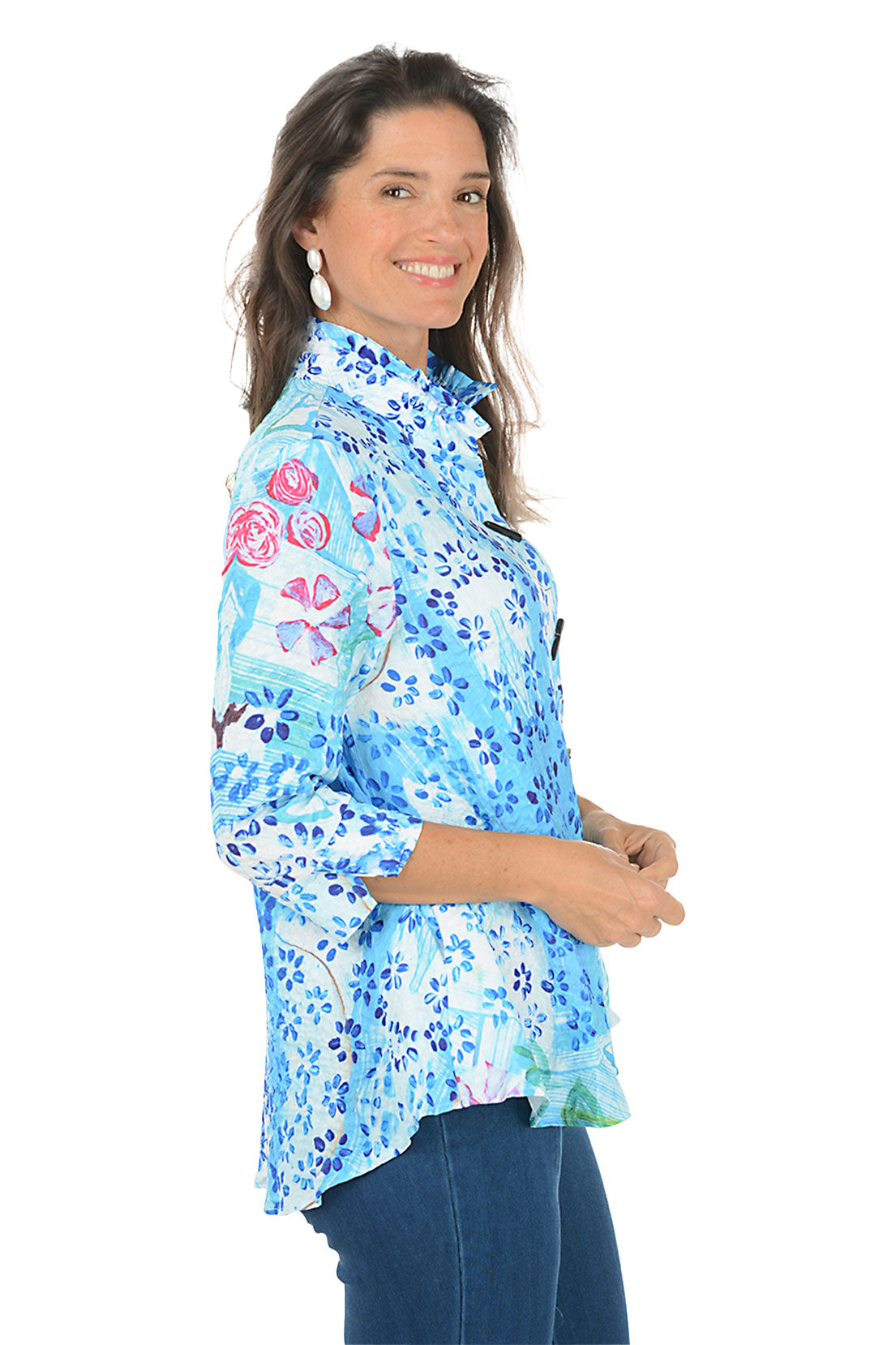 Woman wearing a blue floral blouse on a white background. Side shot.
