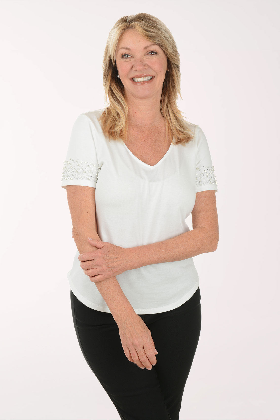 Woman wearing a white blouse with lace details on a white background