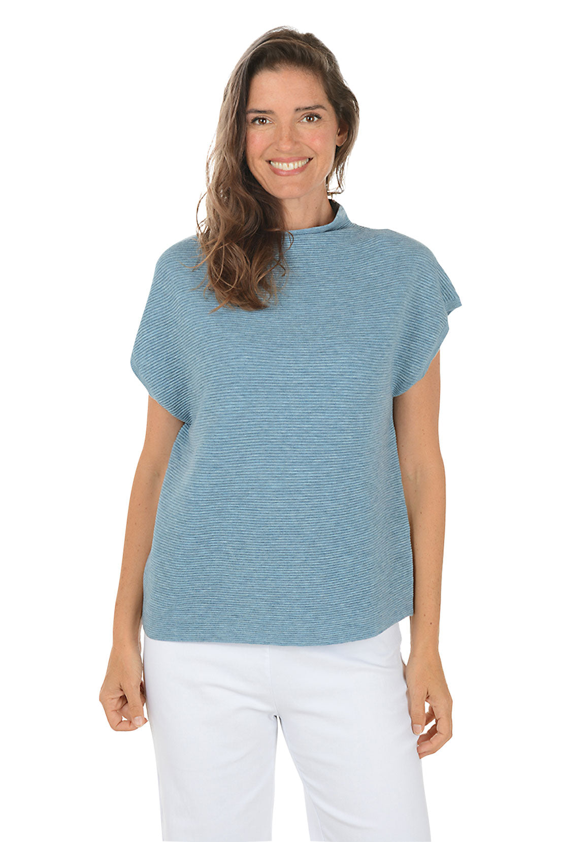 Woman wearing a blue sleeveless top and white pants on a white background.