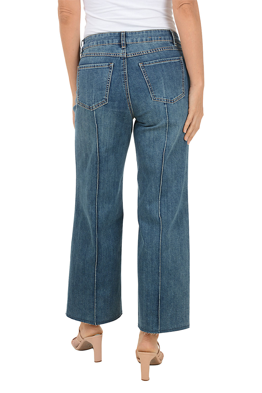 Person wearing blue cropped jeans on a white background. Back shot.