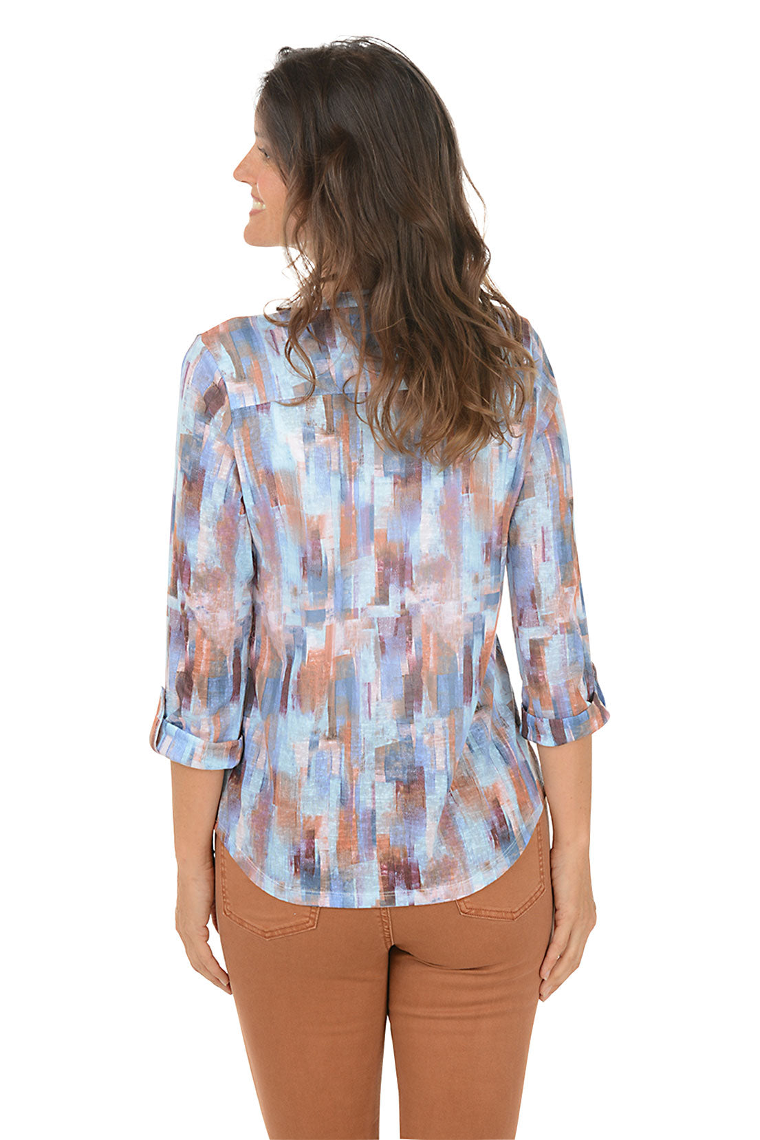 Woman wearing a patterned blouse with brown pants on a white background. Back shot.