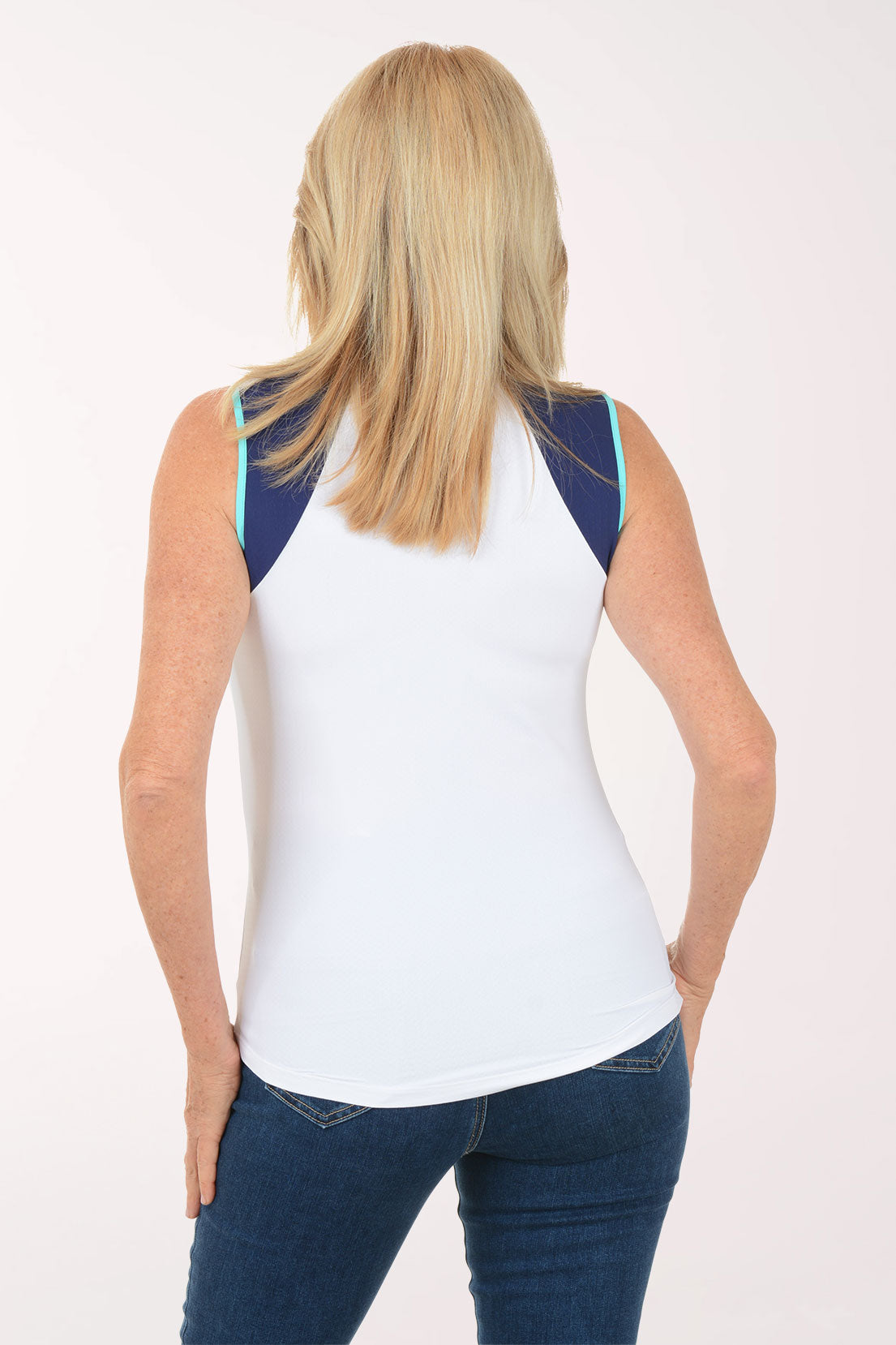 Woman wearing a sleeveless white top with navy accents on a white background
