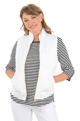 Woman wearing a white quilted puffer vest.