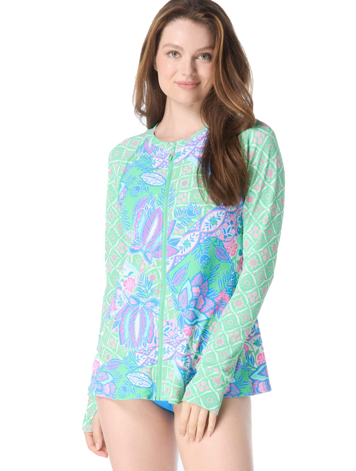 A person wearing a long-sleeved, zip-front, multicolored swim rash guard with a mosaic design.