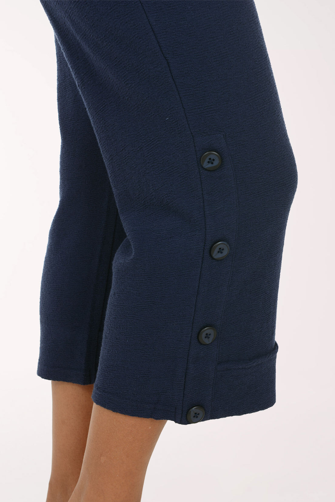 A close-up of the buttons at the hem of a navy crop pant