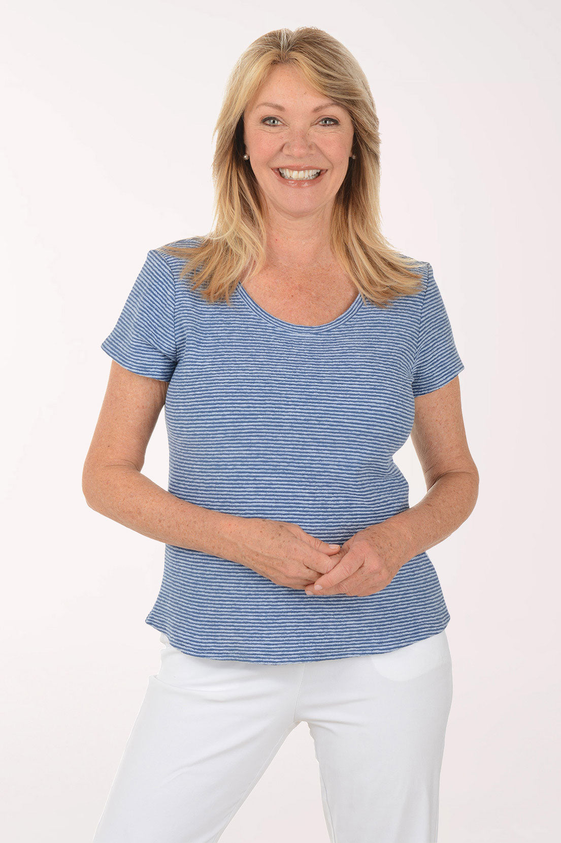 Woman wearing a blue striped shirt and white pants on a white background