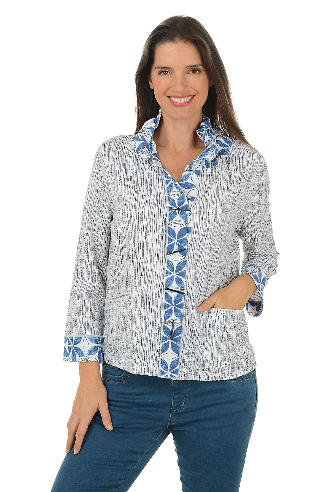 Woman wearing a blue and white patterned jacket with rolled-up sleeves on a white background