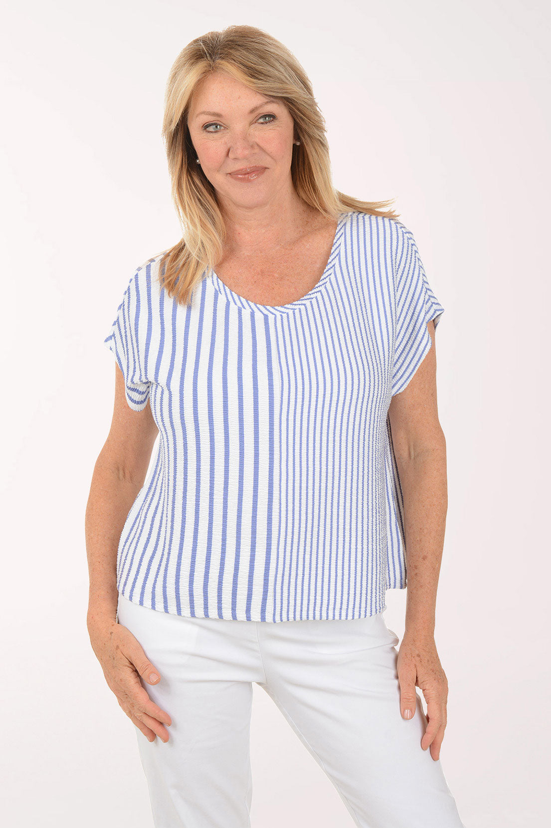 Woman wearing a blue and white striped top and white pants on a white background