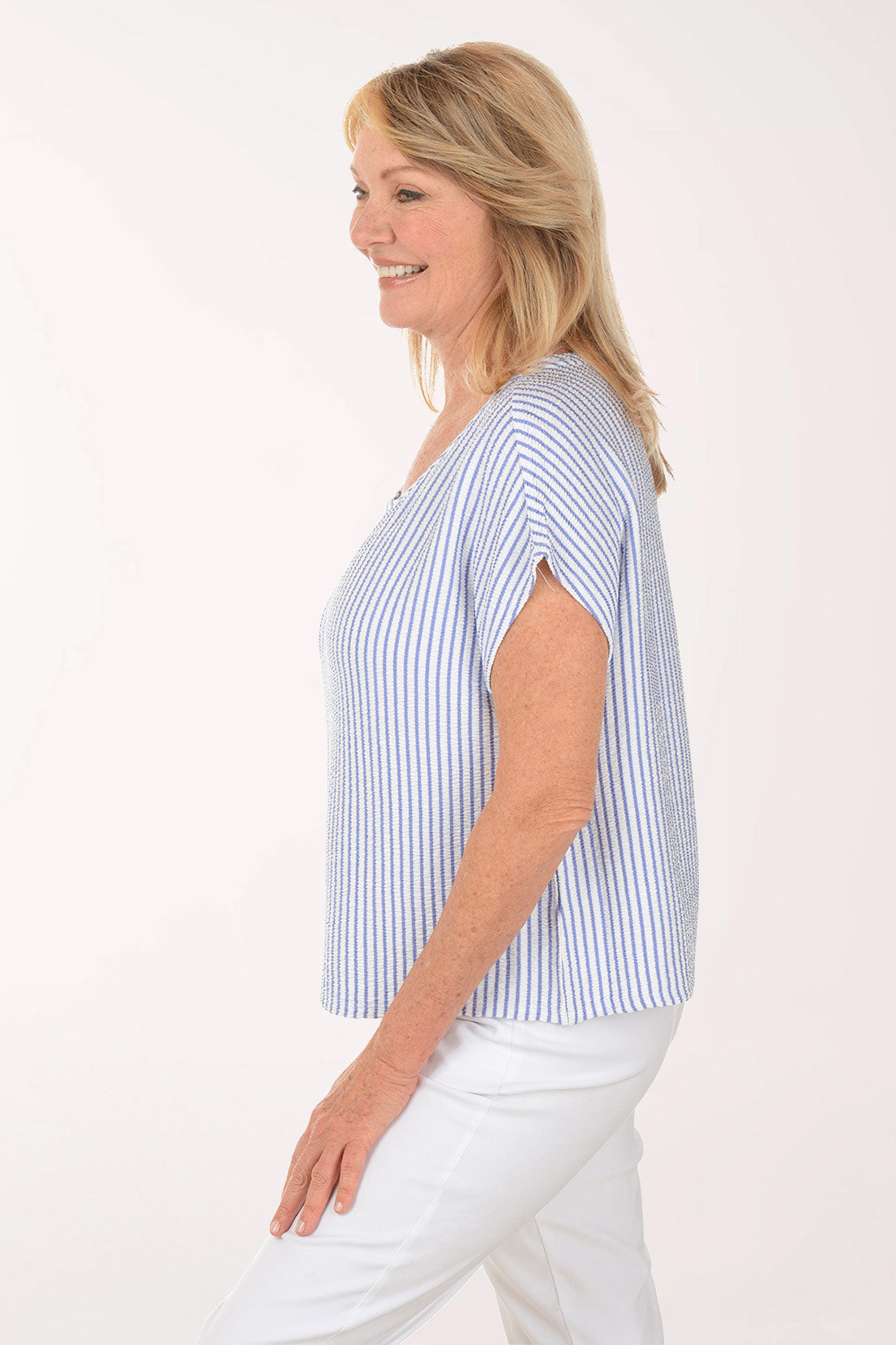 Woman wearing a blue and white striped top and white pants on a white background
