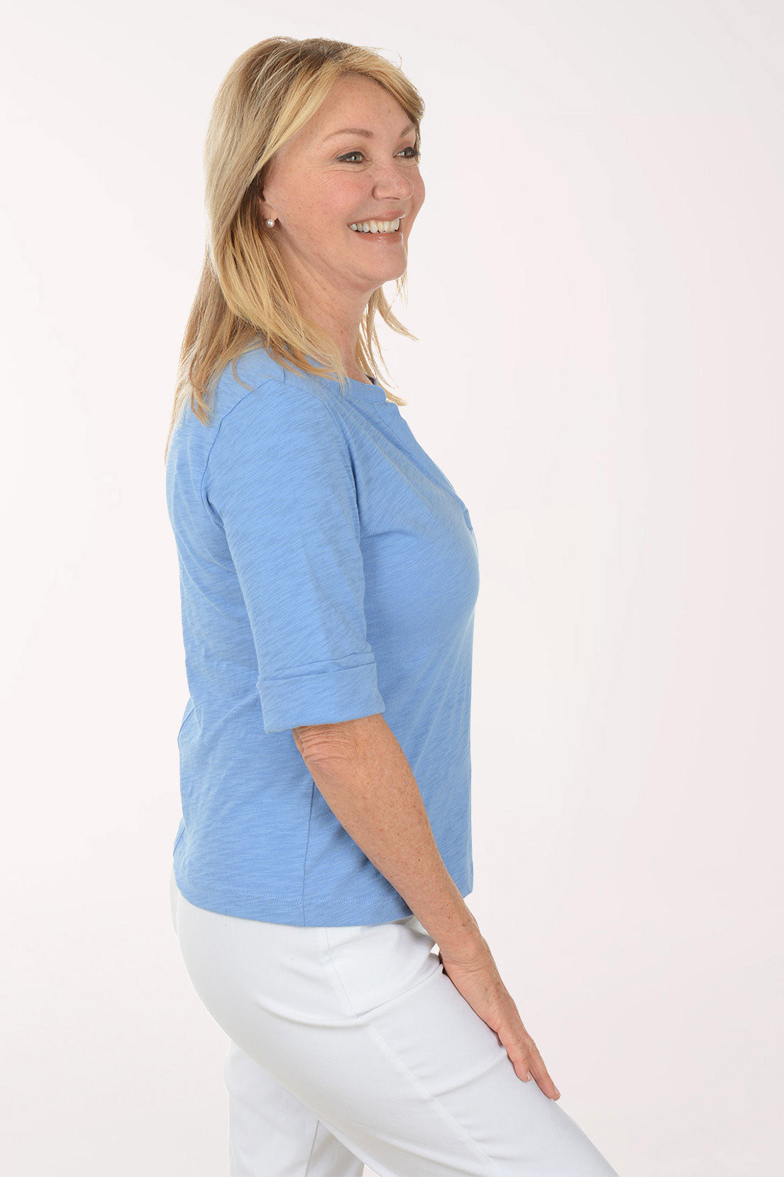 Woman wearing a blue top and white pants on a white background