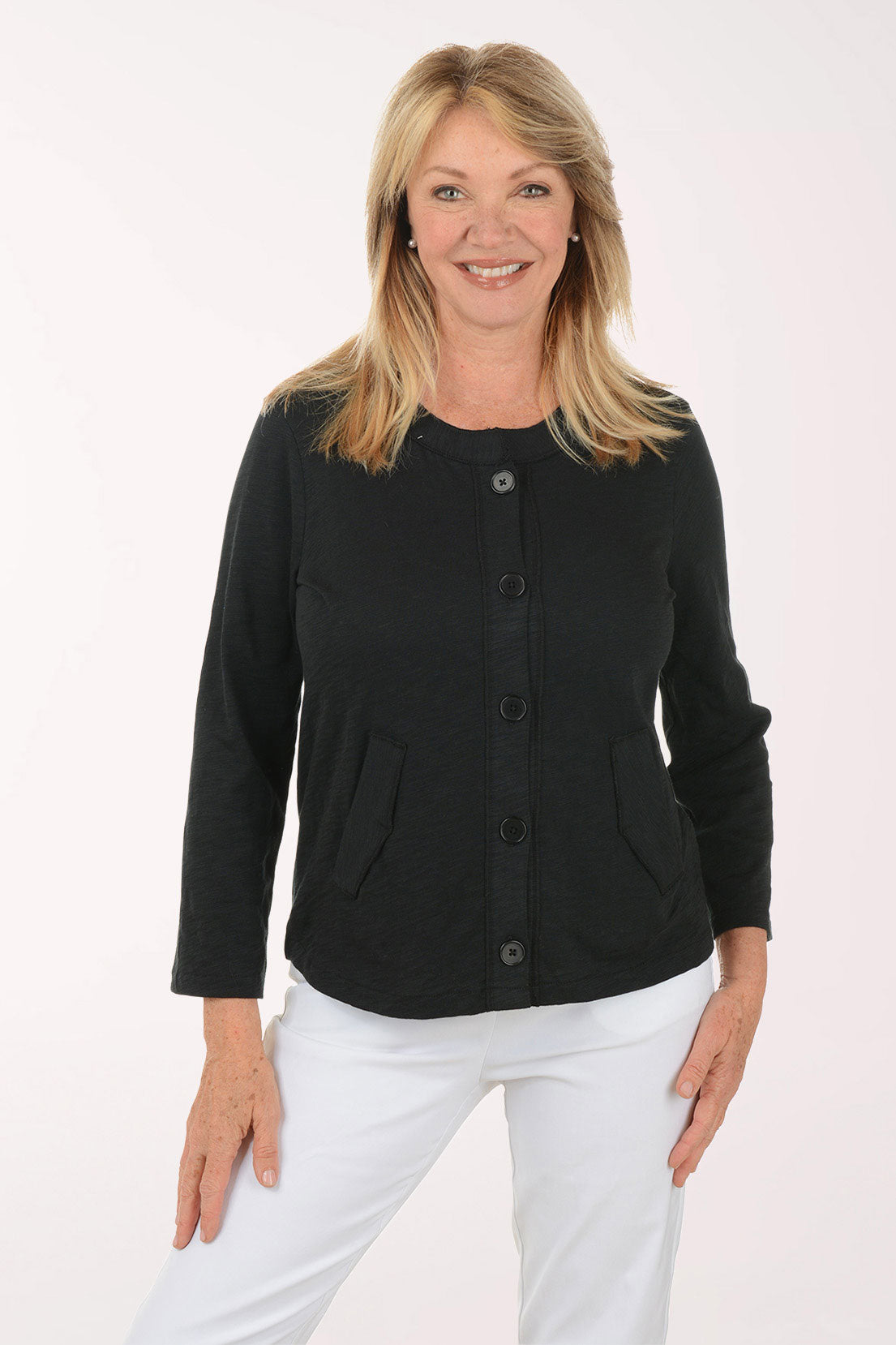 Woman wearing a black cardigan and white pants on a white background