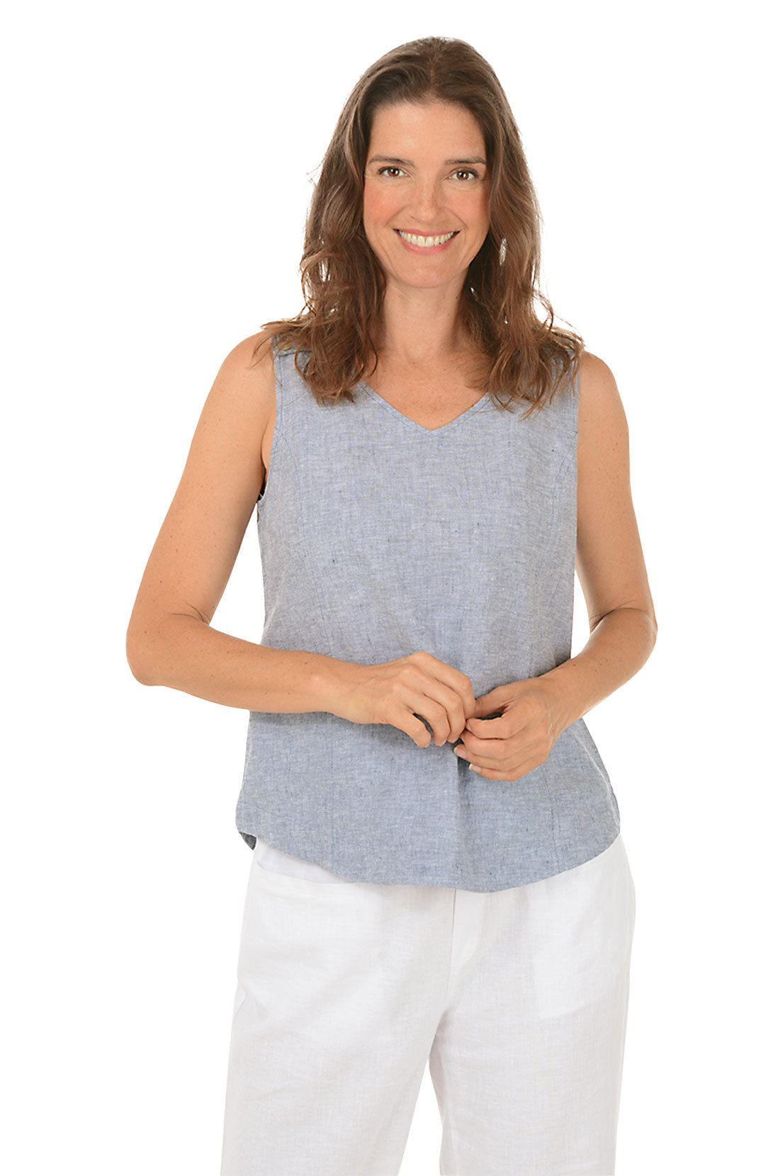 A front shot of a model wearing a indigo sleeveless tank top with a V-neckline and triple button styling on shoulder straps, paired with white pants.