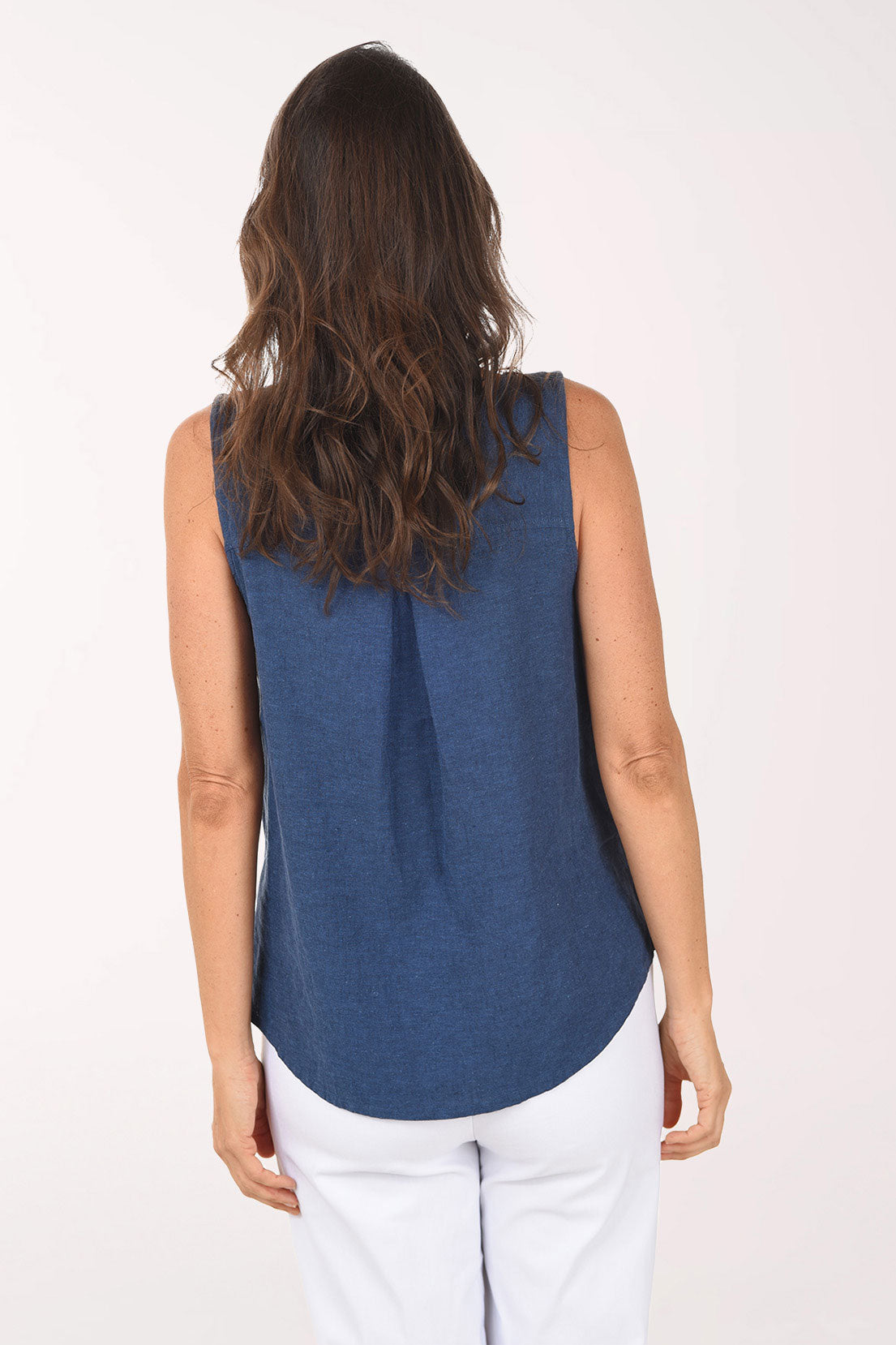 Woman wearing a blue sleeveless top with buttons on a white background