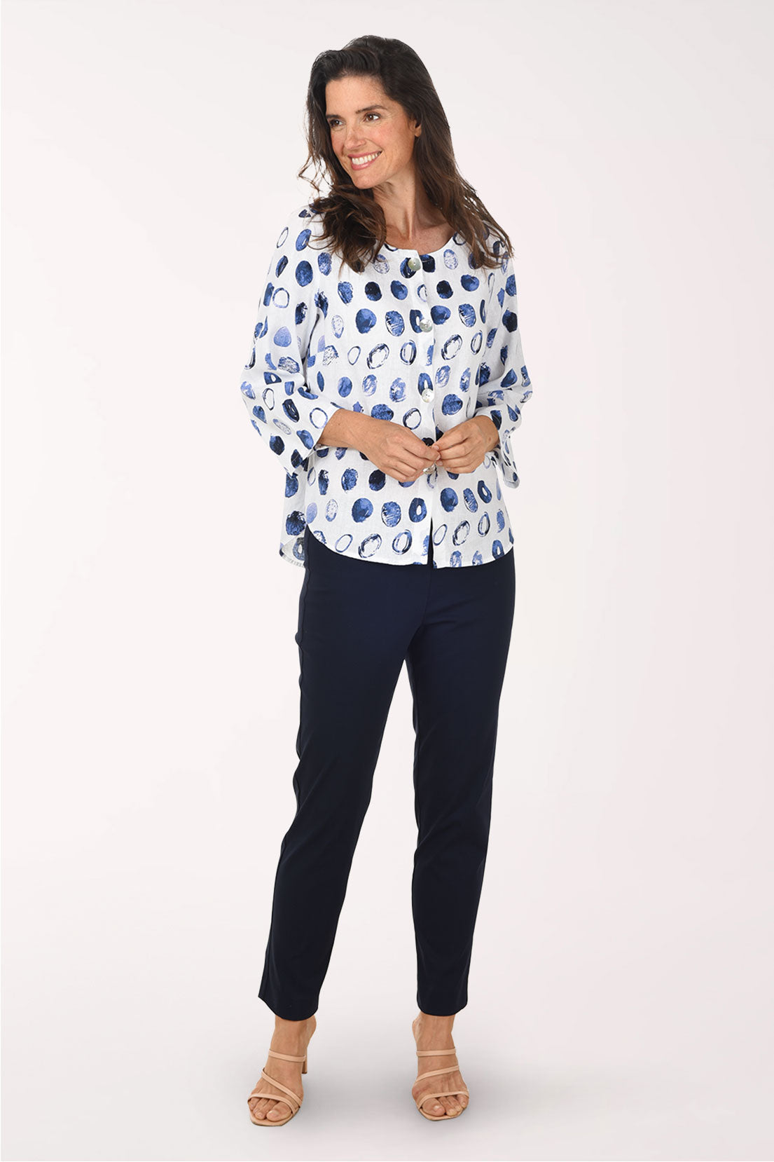 Woman wearing a patterned blouse and black pants on a white background