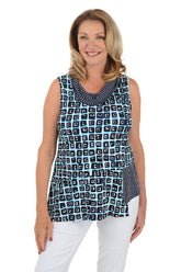 A front shot of a model wearing a sleeveless knit top with a cowl neckline and asymmetrical patchwork construction. The top is primarily black with white geometric patterns and contrasting fabric accents.