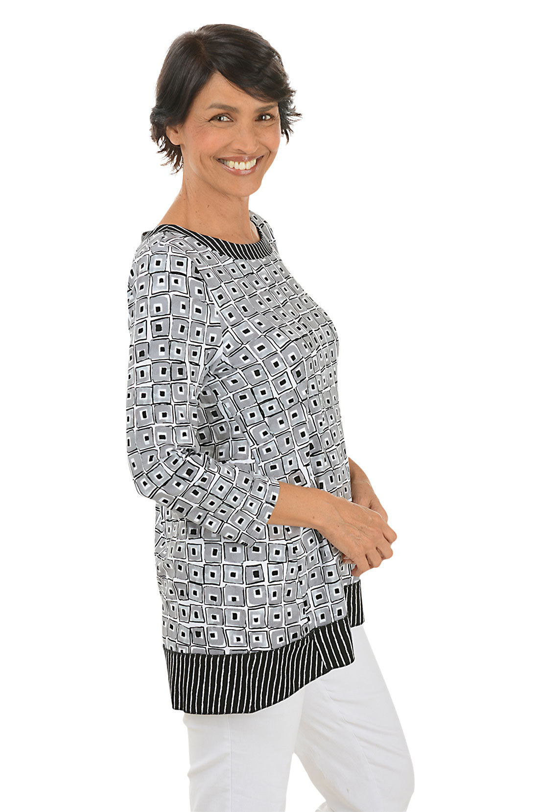 A side shot of a model wearing a black and white geometric patterned tunic with a pleated back detail and a scoop neckline.