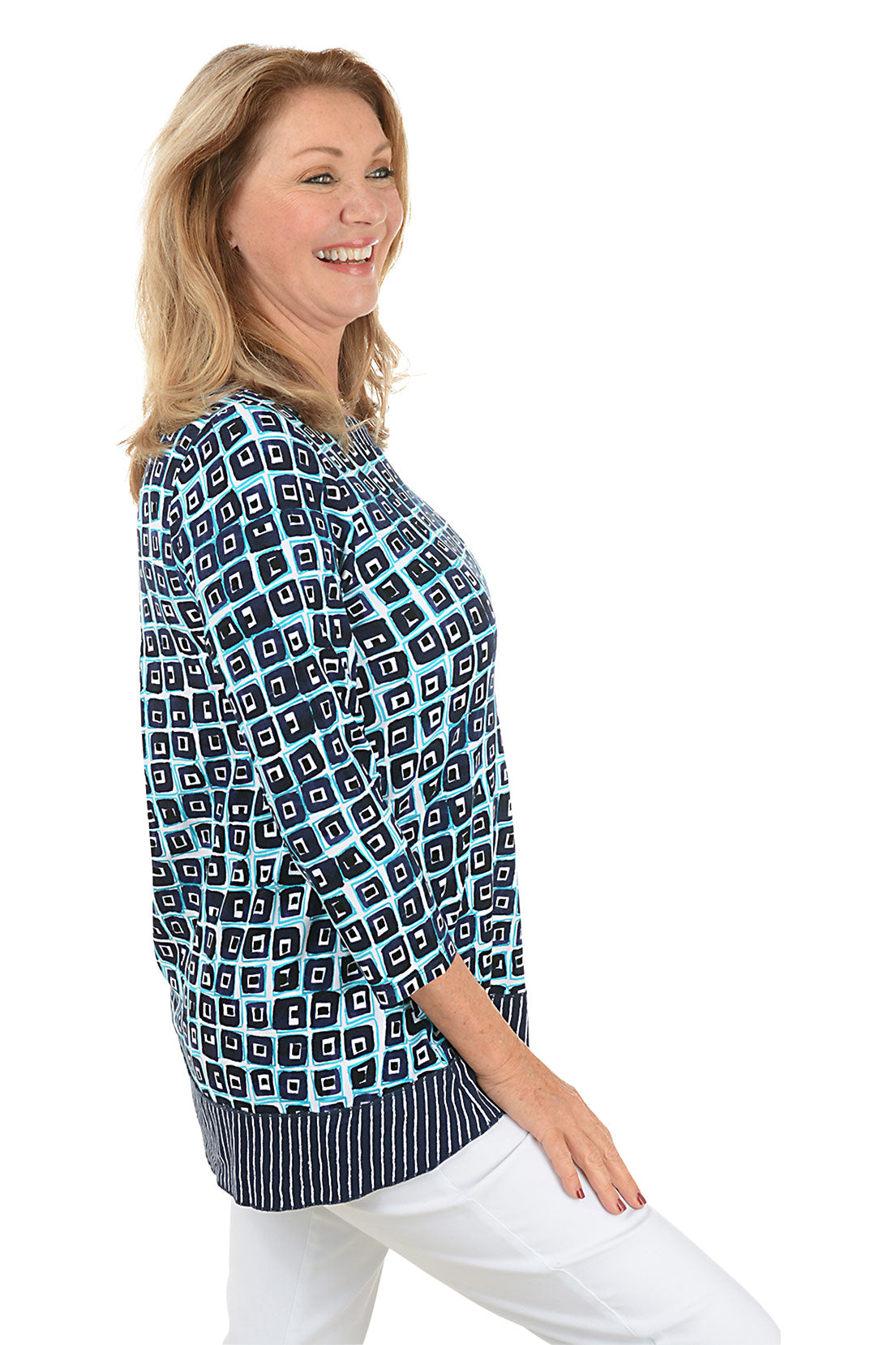 A side shot of a model wearing a blue and white geometric patterned tunic with a scoop neckline and pleated detail on the back.