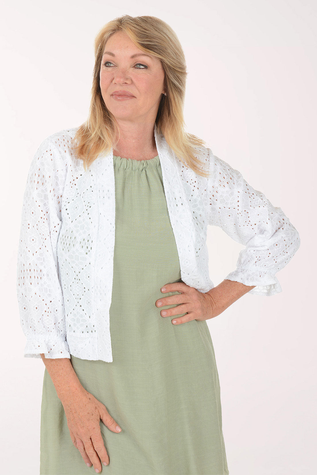 Woman wearing a white lace shrug over a green dress on a white background