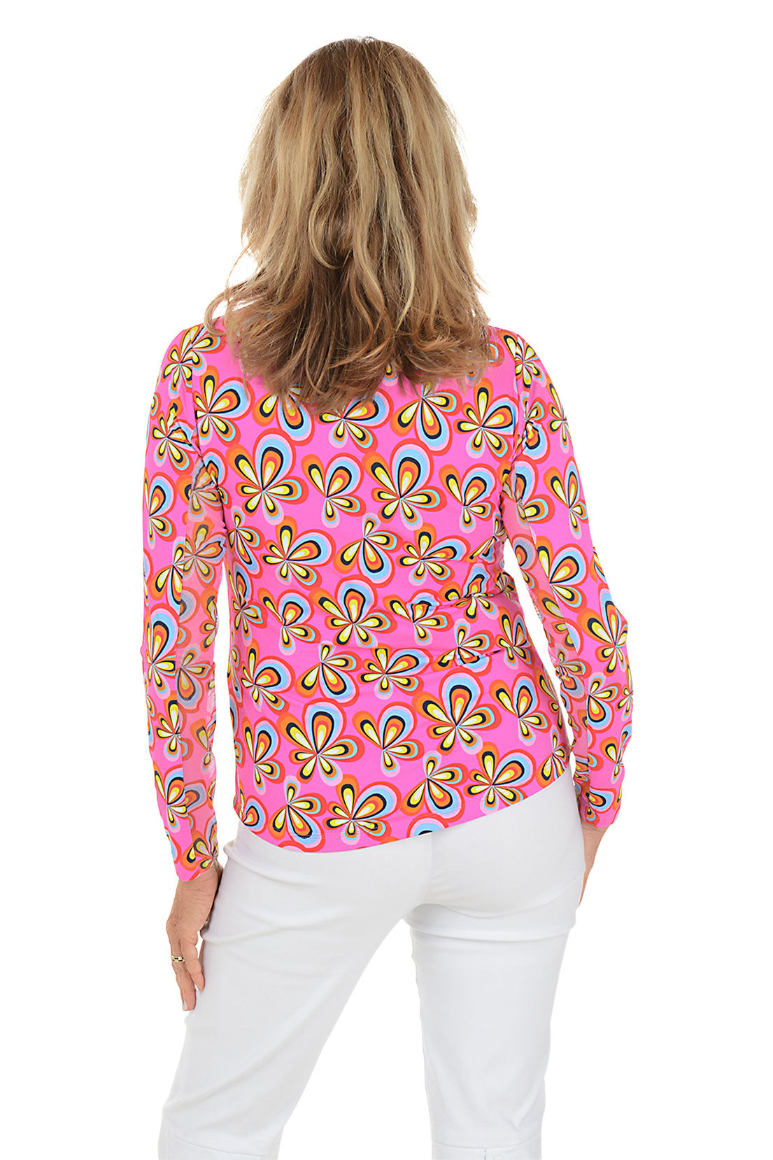 Woman wearing a pink floral patterned blouse with white pants on a white background. Back shot.
