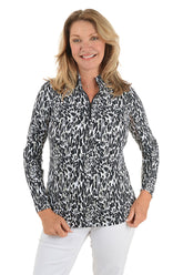 Woman wearing a patterned blouse and white pants on a white background.