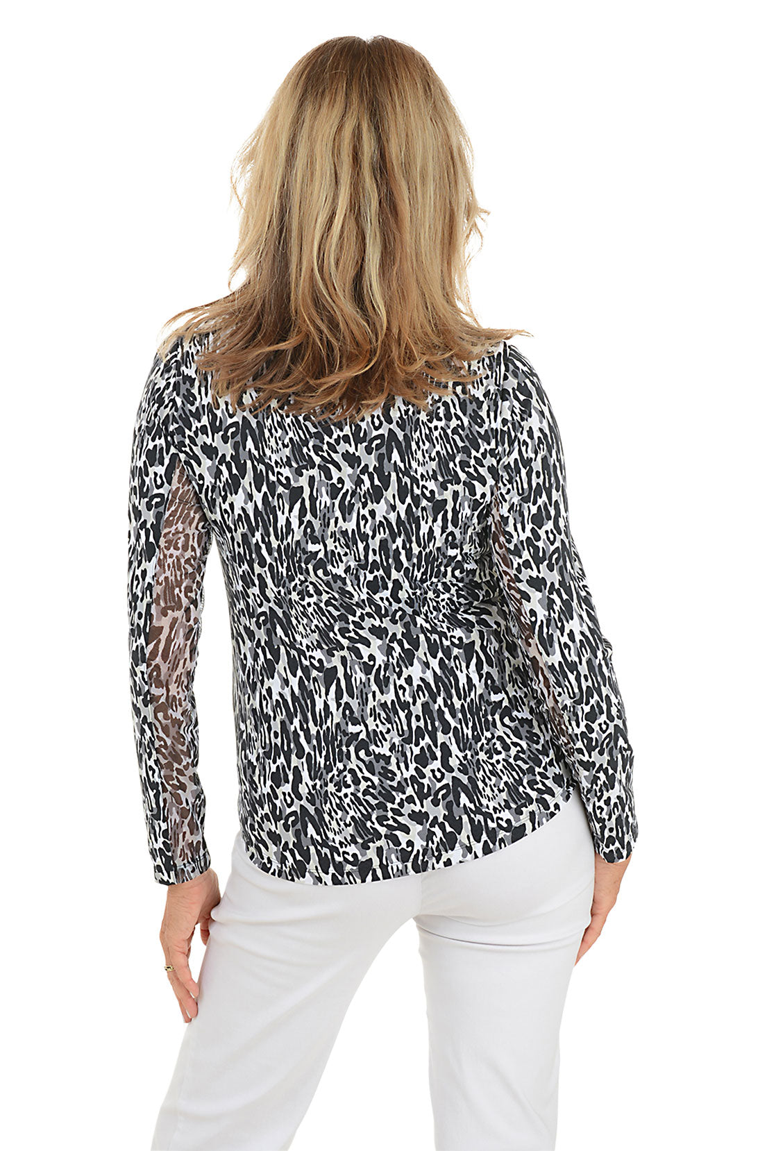 Woman wearing a patterned blouse and white pants on a white background. Back shot.