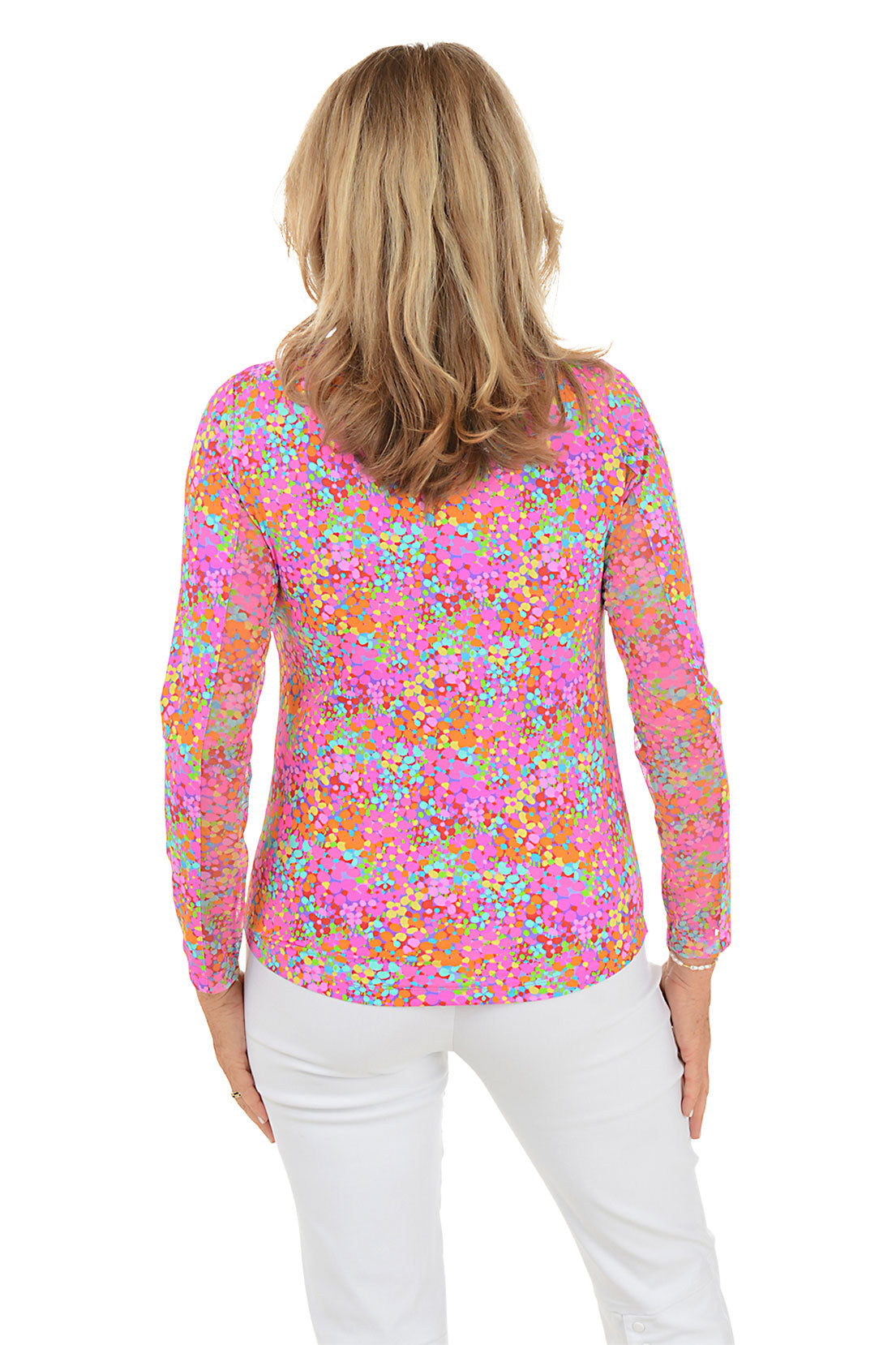 Woman wearing a colorful floral blouse with white pants on a white background. Back shot.