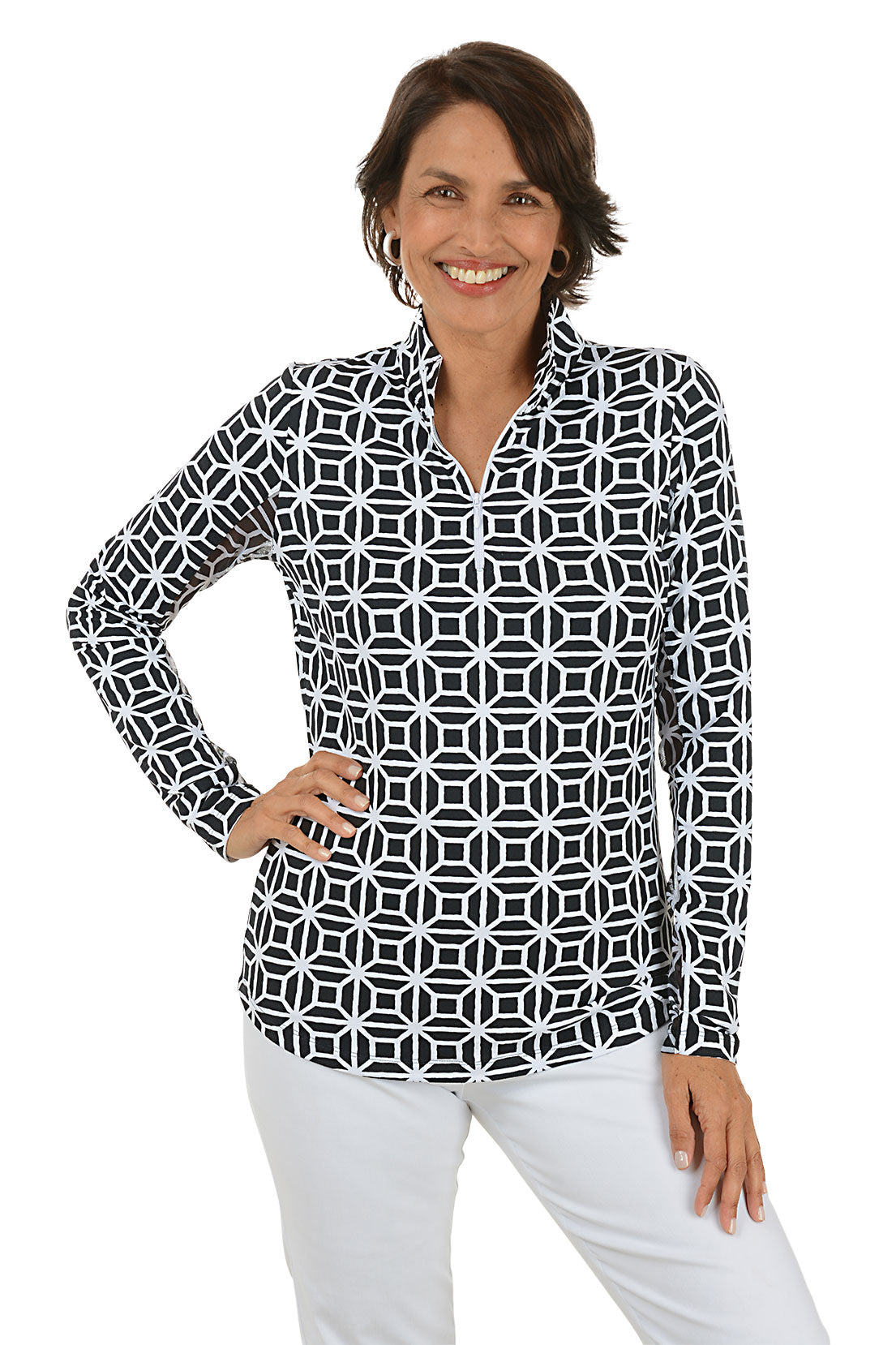 Woman wearing a black geometric patterned shirt with white pants on a white background