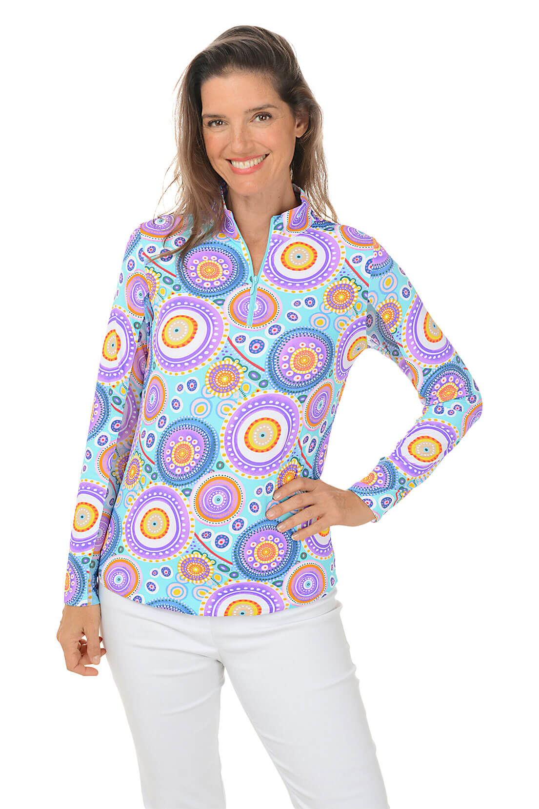 A woman wearing a long sleeve sun shirt with a multicolored geometric mandala pattern, a mock neck, and a quarter-zip.