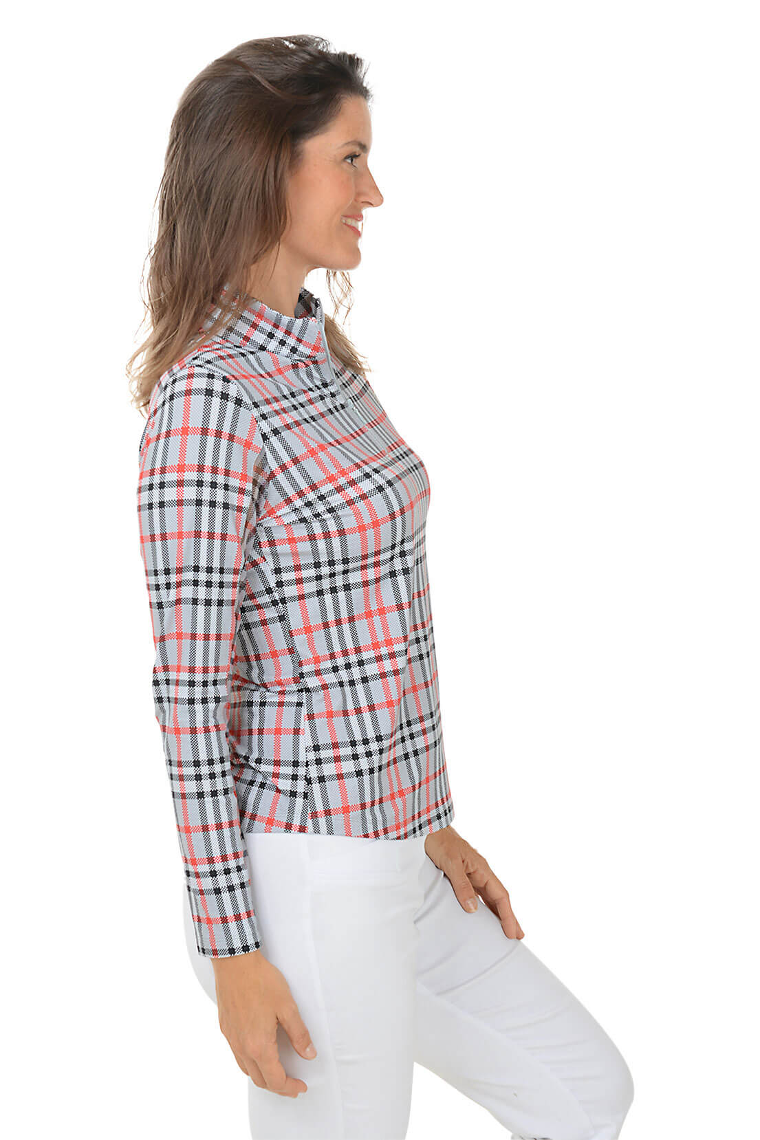 A woman wearing a red, black, and white plaid sun shirt with a mock neck and quarter-zip styling, paired with white pants. Side shot.