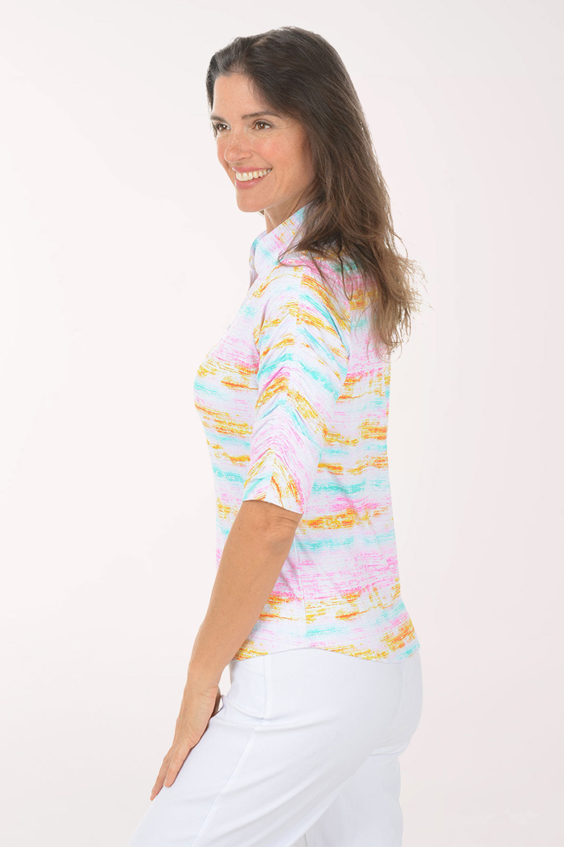 Woman wearing a colorful striped shirt and white pants on a white background