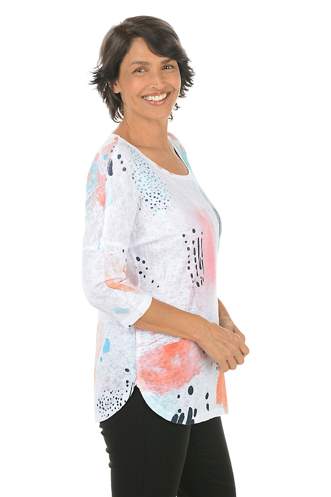 Woman wearing a colorful abstract patterned top on a white background. Side shot.