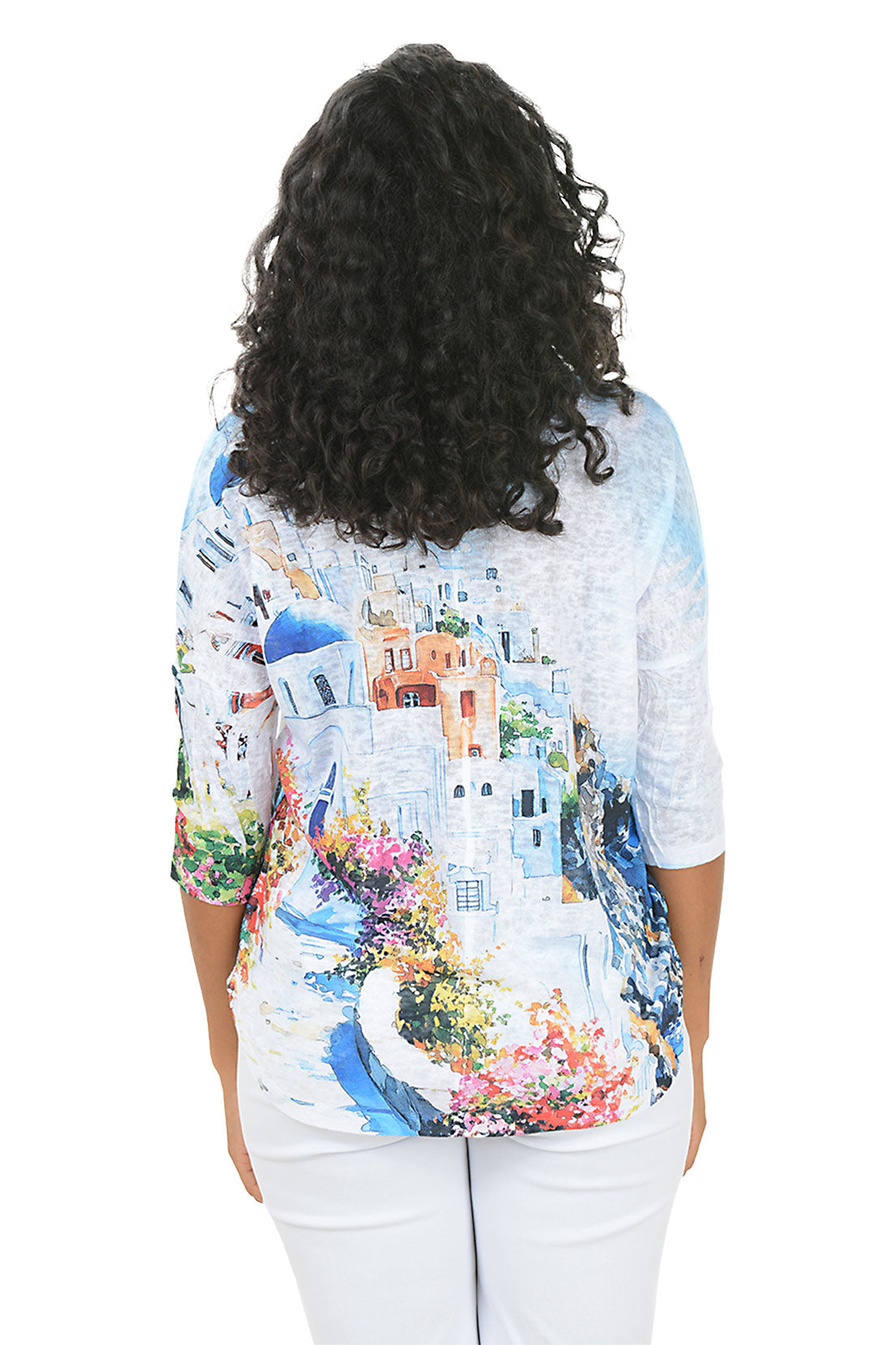 Woman wearing a colorful print top with a scenic design on a white background. Back shot.