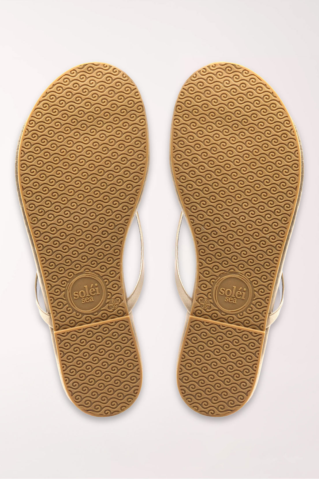 Pair of champagne gold flip-flops on a white background