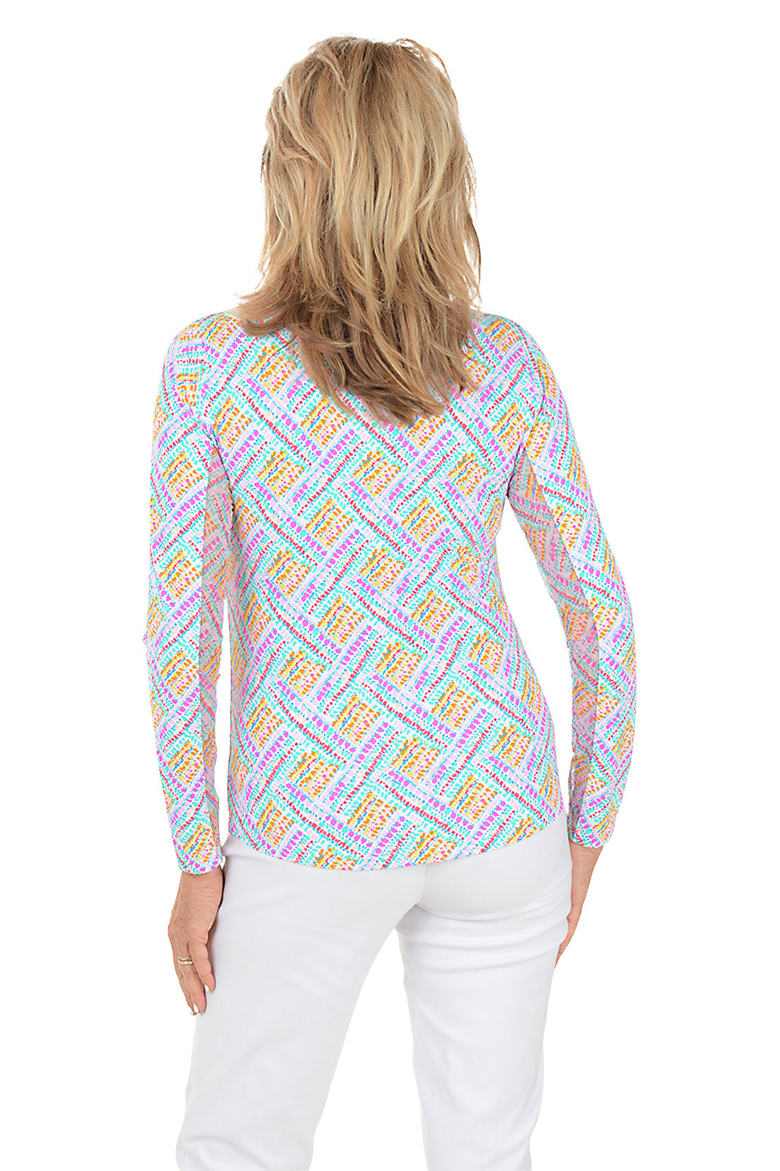 Woman wearing a colorful patterned blouse with white pants on a white background. Back shot.
