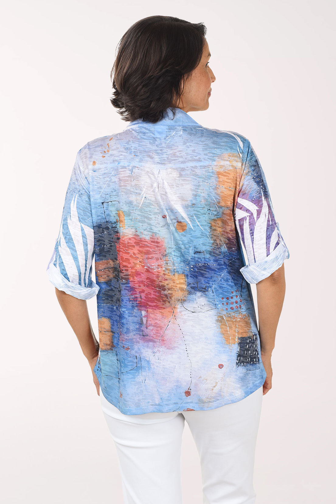 Woman wearing a colorful abstract patterned blouse on a white background