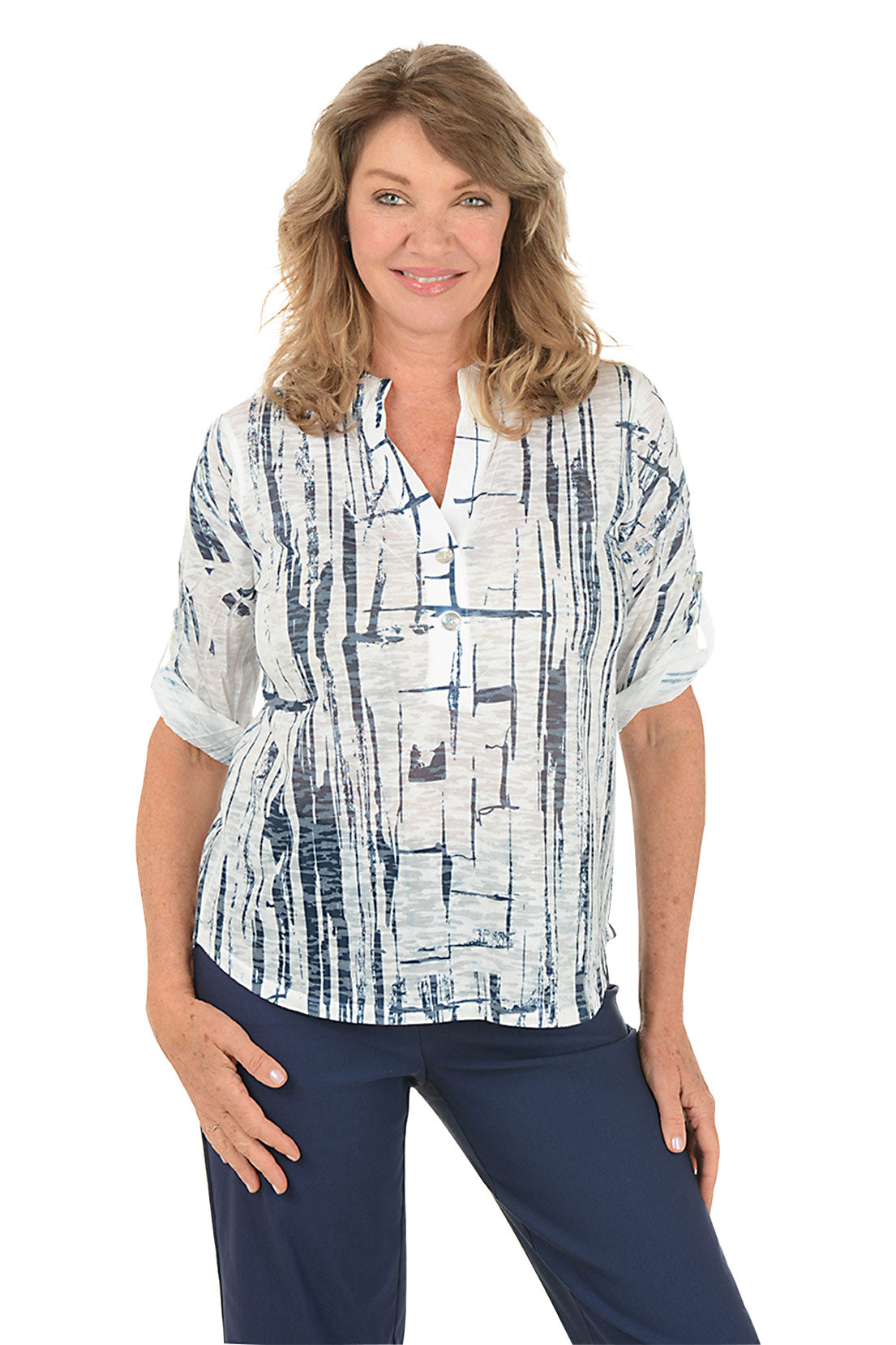 A woman wearing a white and navy 3/4 rolled sleeve top with a button detail and abstract pattern.