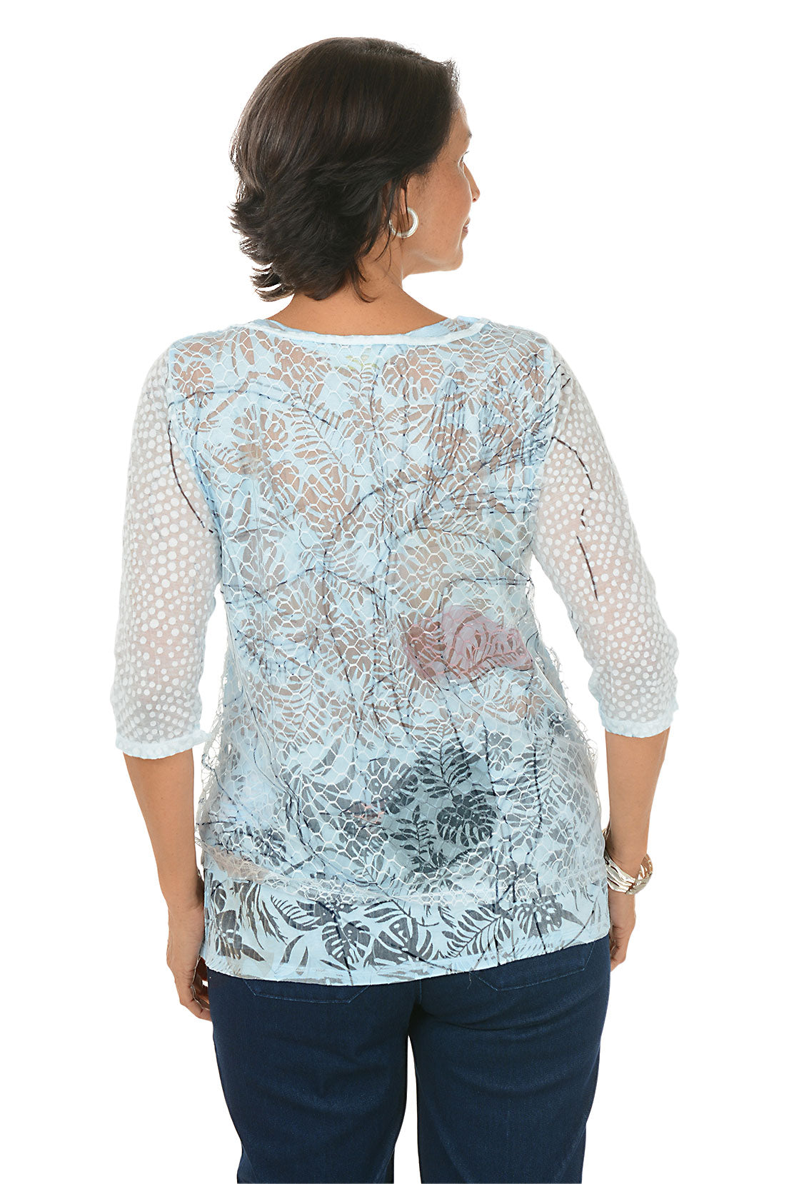 Woman wearing a light blue floral patterned top on a white background. Back shot.