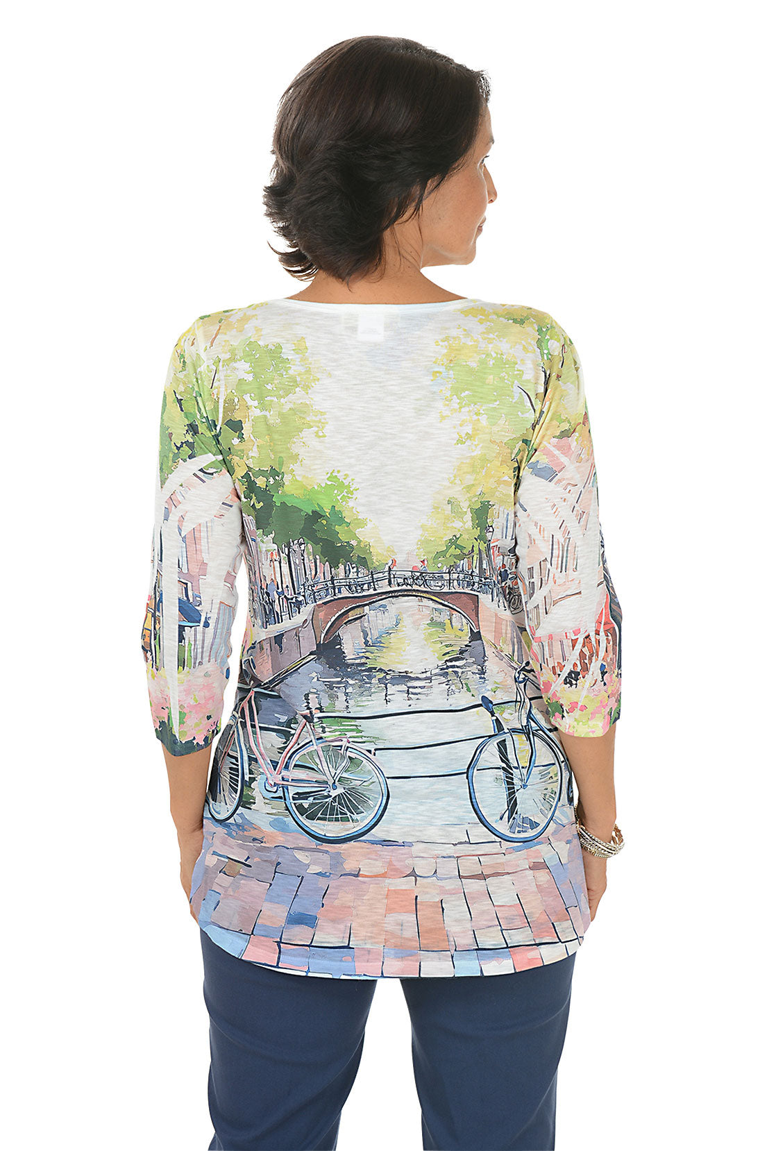 Woman wearing a colorful shirt with a bridge and bicycle design on a white background. Back shot.