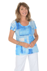 A woman wearing a blue short sleeve top with a blue and white abstract pattern.