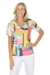 A woman wearing a short sleeve multicolored top with an abstract pattern.
