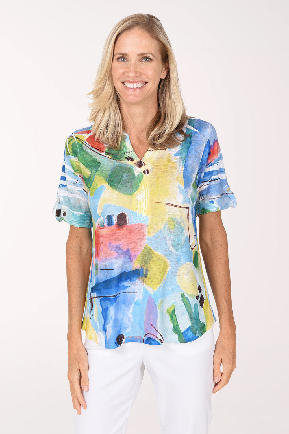 Model wearing the Impulse Colorful Abstract Sequin Accented Polo Top, a bright watercolor print in cobalt, yellow, coral and green, over white pants, front view